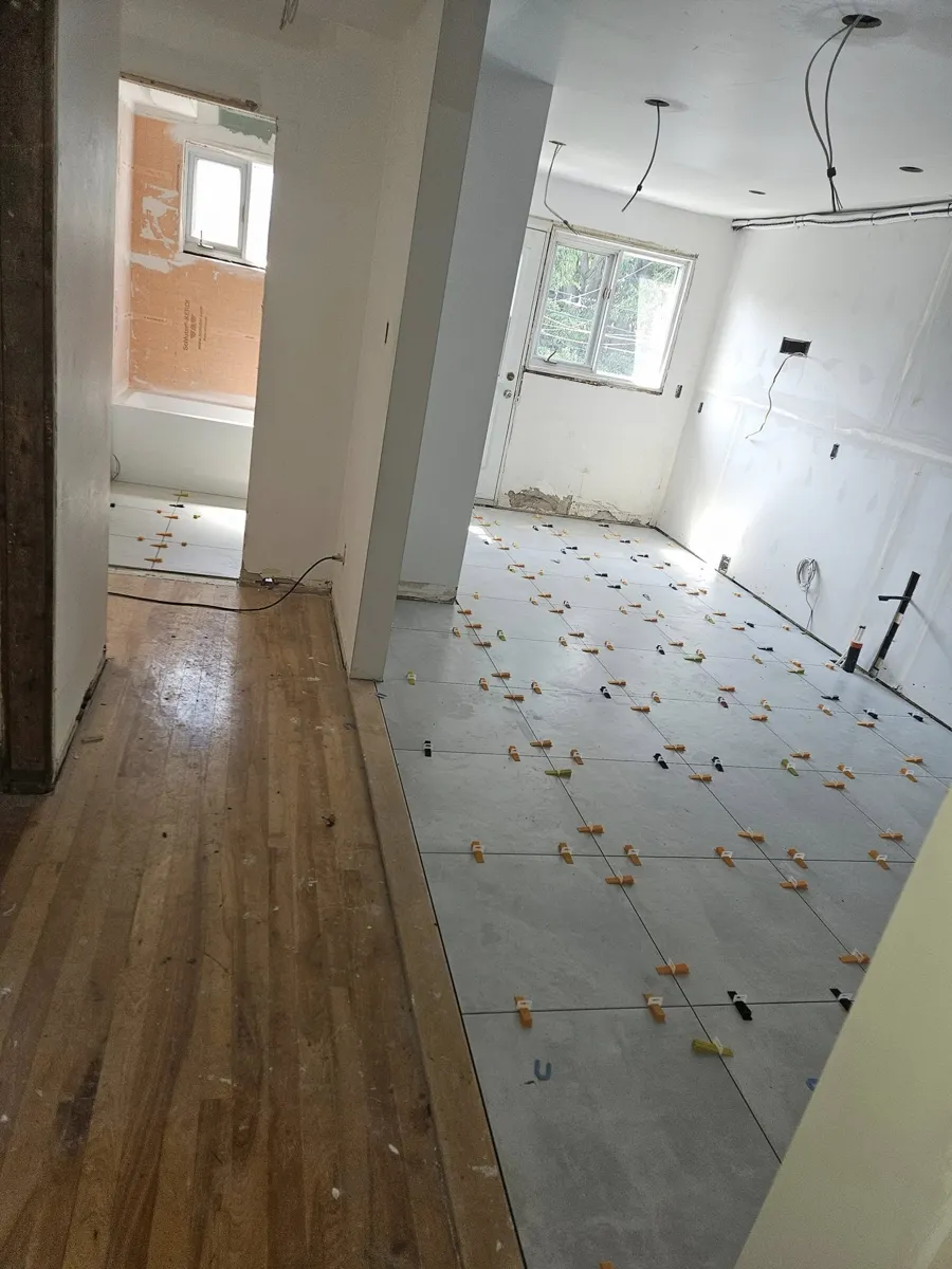 Pose d'un plancher grand format avec clips de nivellement, pour que chaque carreau repose à plat dans la colle