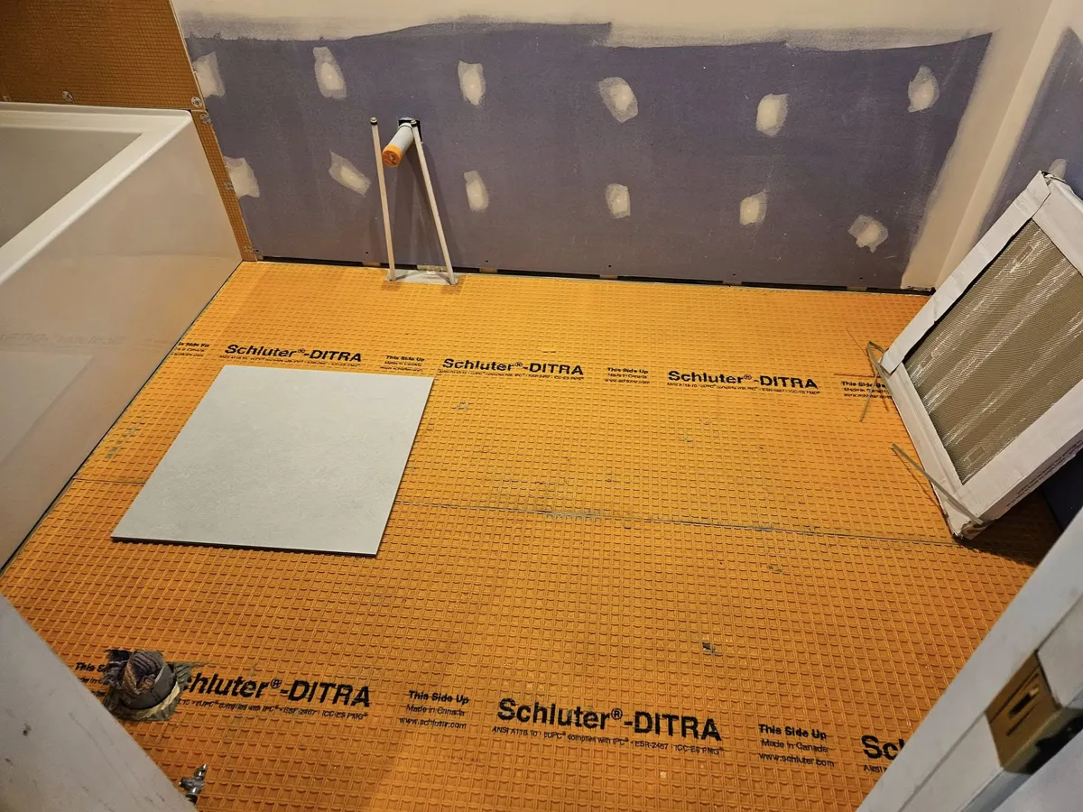 Membrane Ditra posée sur tout le plancher de la salle de bain, avant la céramique