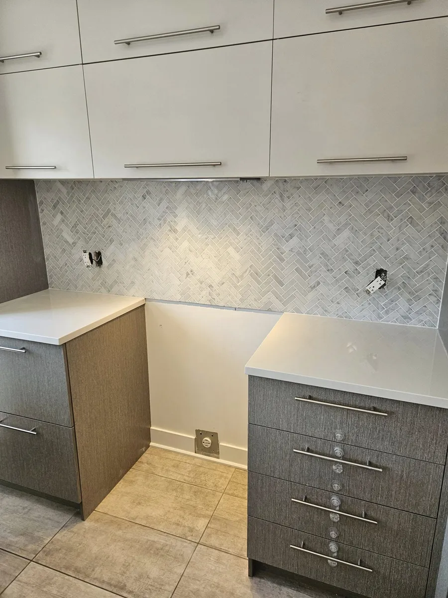 Dosseret en mosaïque à chevrons de marbre gris et blanc, découpes des prises électriques prêtes