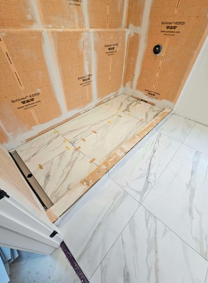 Pose de la céramique sur le fond de douche, les murs encore en membrane