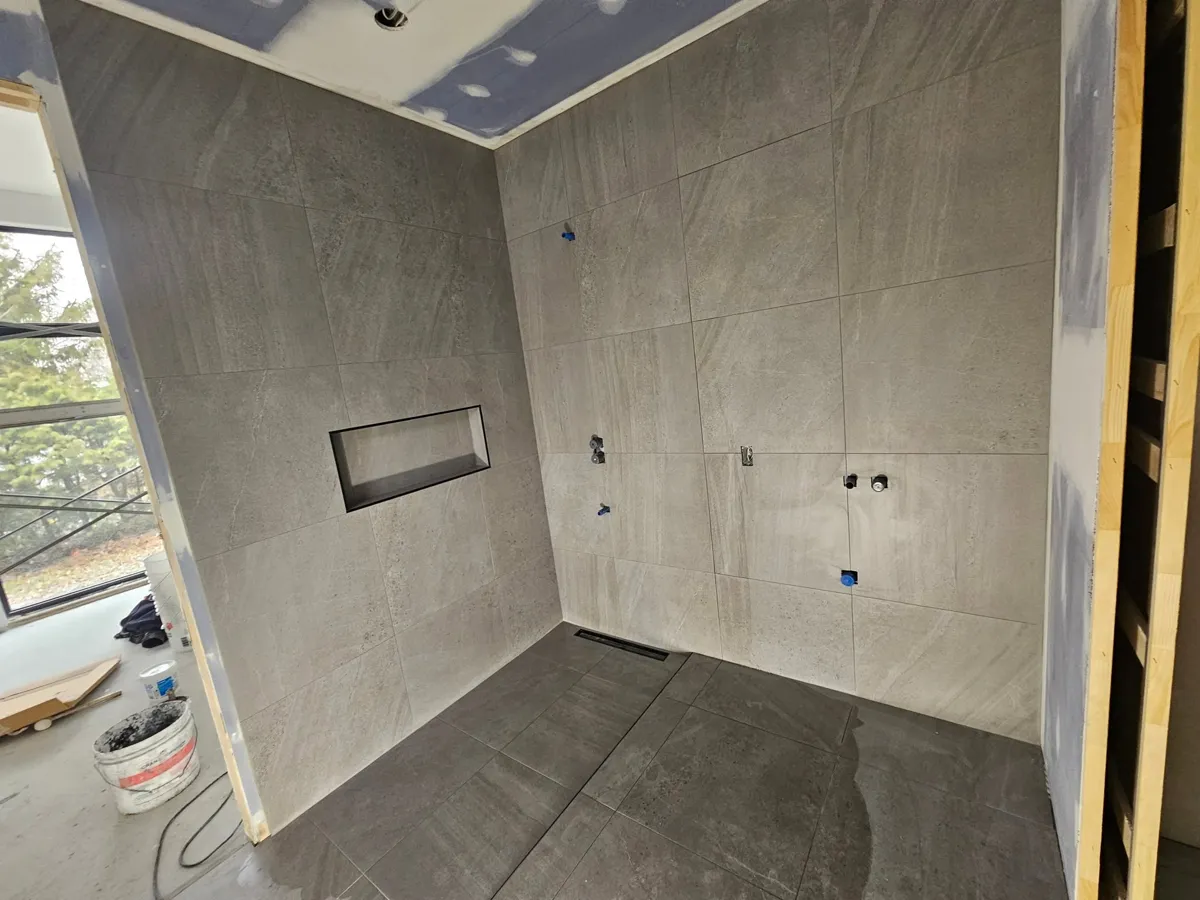 Douche à l'italienne en 24 x 24 avec alcôve intégrée et drain linéaire au pied du mur