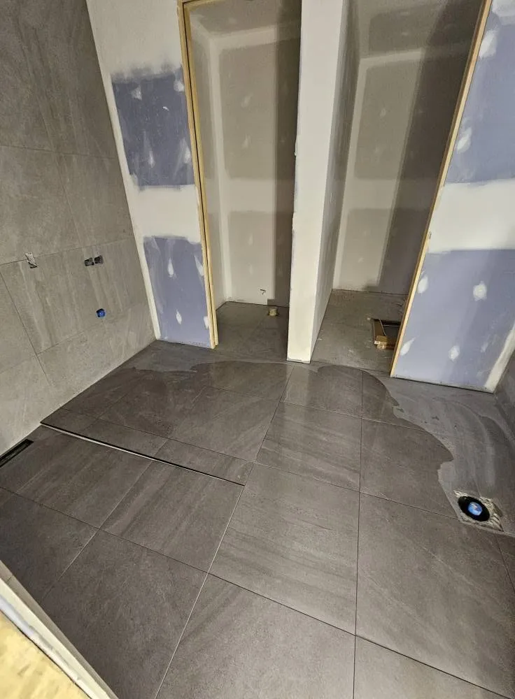 Plancher de la salle de bain en grand format, joints réguliers jusqu'aux cloisons