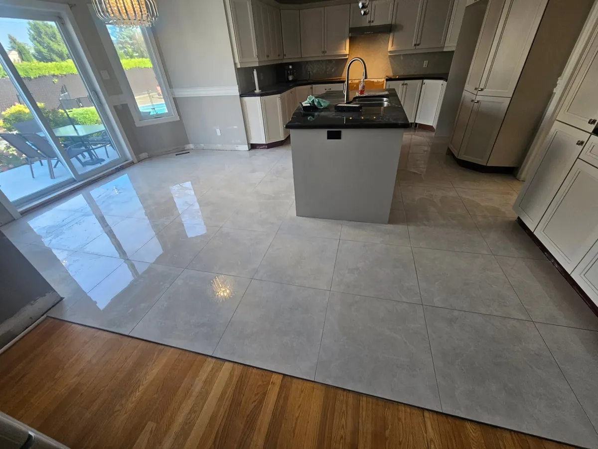 Nouveau plancher grand format poli autour de l'îlot, jusqu'au plancher de bois de la pièce voisine