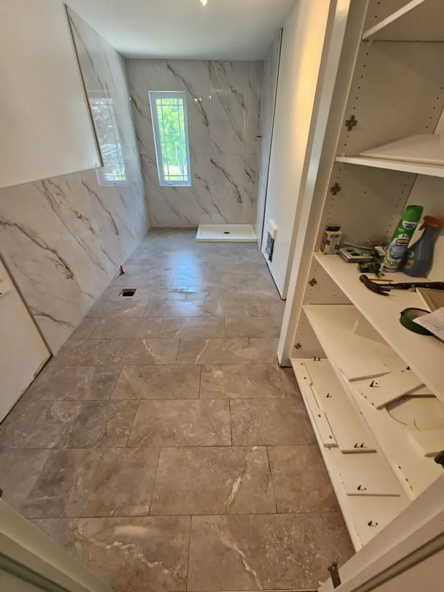 Plancher de la salle de bain en grand format taupe, posé sur membrane Ditra