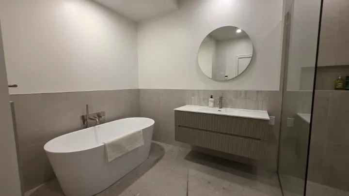 Vue d'ensemble : bain autoportant, meuble-lavabo suspendu et demi-mur de céramique