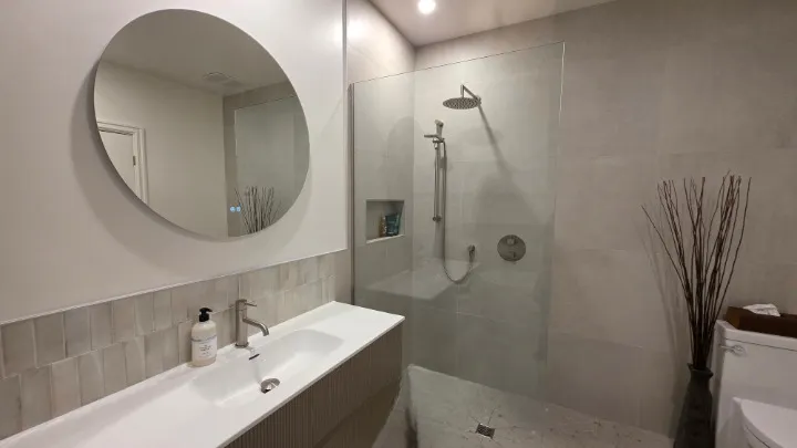 Douche à l'italienne fermée par une paroi de verre fixe, avec niche encastrée et plancher continu sans seuil