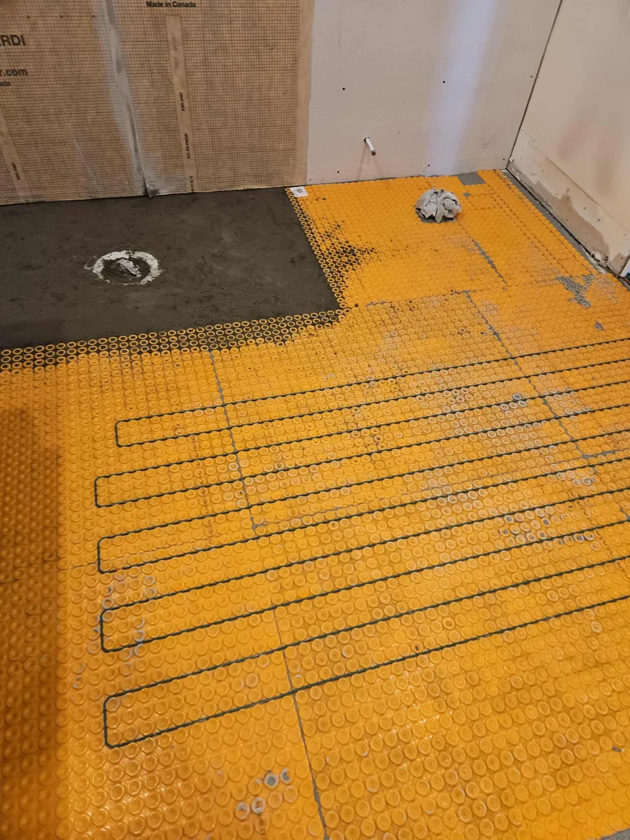 Membrane Ditra-Heat et câble chauffant sur tout le plancher, à côté du fond de douche préparé