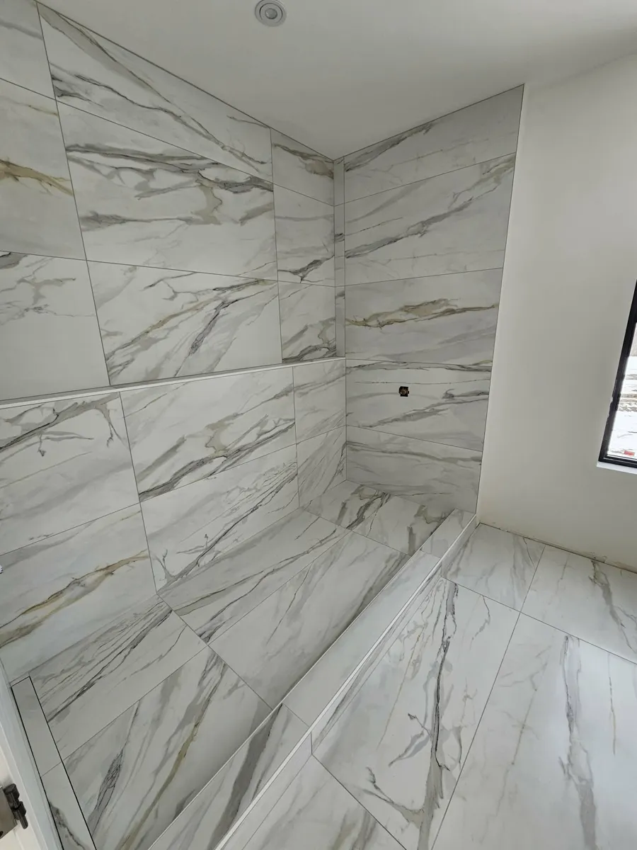 Plancher de Calacatta qui se prolonge jusque dans la douche, veines alignées d'un carreau à l'autre