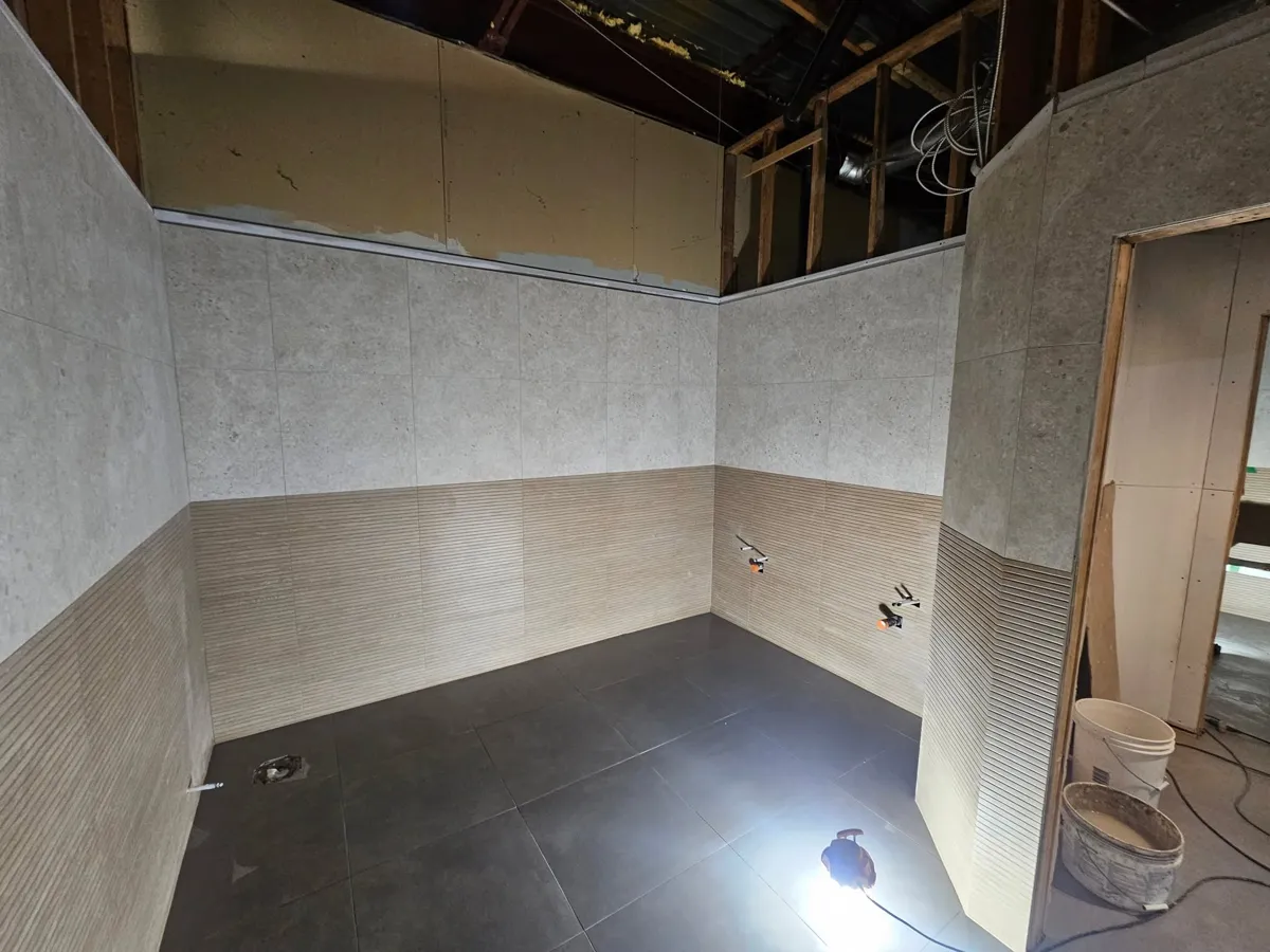 Vue d'ensemble : 24 x 48 vertical à texture striée en bas, 24 x 24 gris pierre en haut et plancher 24 x 24 anthracite
