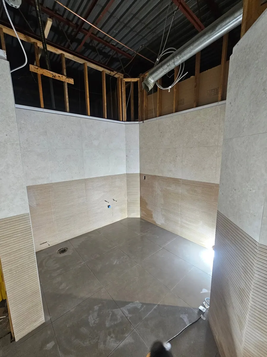 Salle de bain avec drain de plancher, pente et joints alignés en grand format